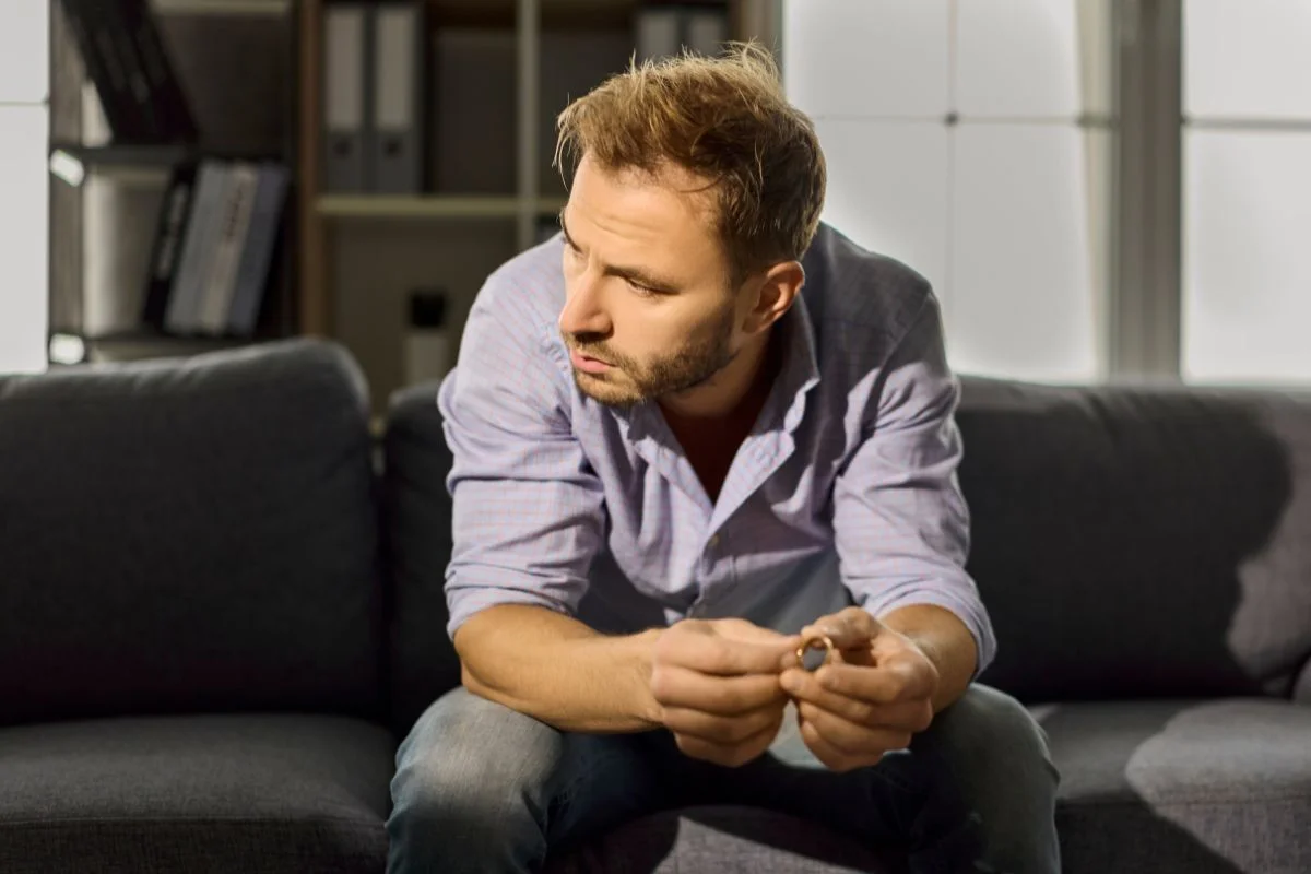 Mann sitzt nachdenklich und ratlos allein auf dem Sofa
